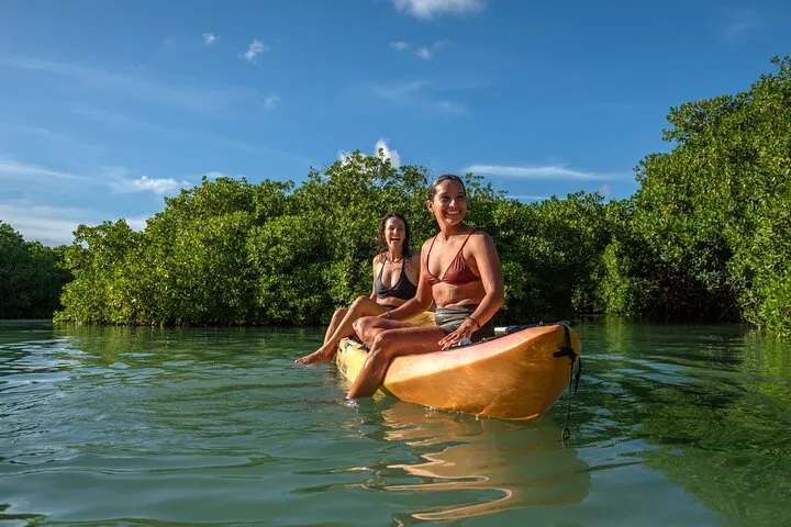 Kayakers paddling a narrow mangrove channel at Lac Bay on a Bonaire snorkeling tour of the mangroves